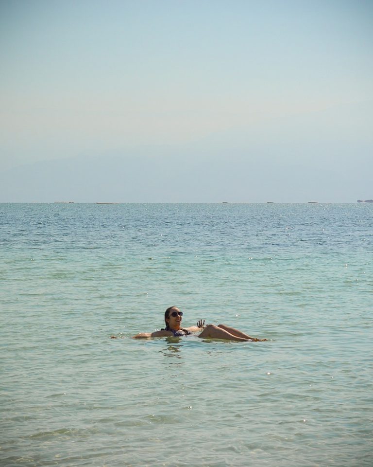 Rachel flutuando com as pernas dobradas no Mar Morto, em Israel.
