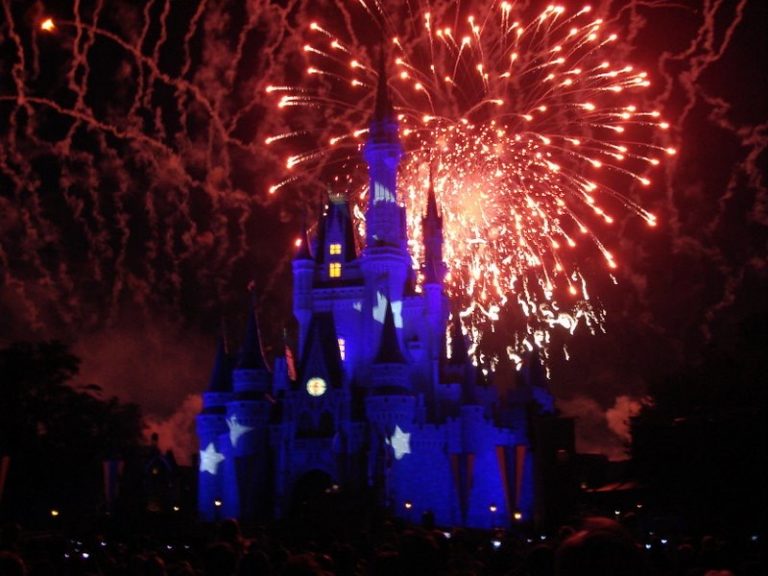 Fogos de artifício por trás do Castelo da Cinderela, que está iluminado de azul e estrelas brancas.