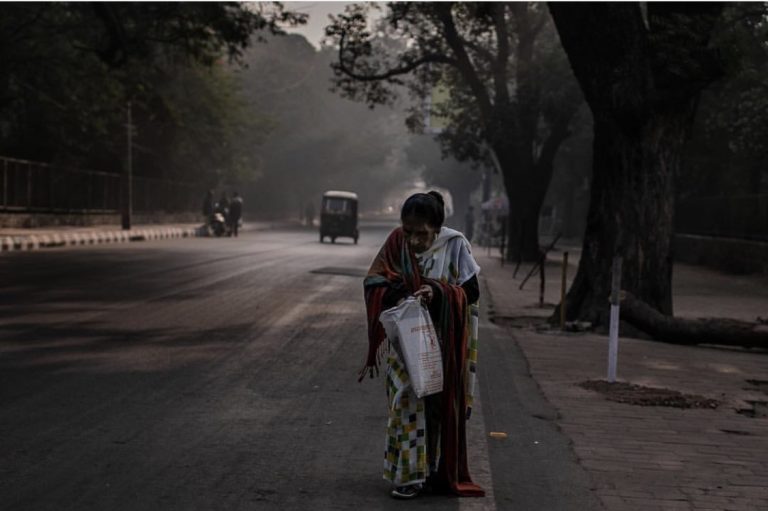 Senhora mexe na bolsa em meio à poluição de Délhi