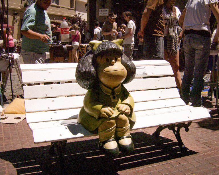 Estátua da personagem Mafalda, do artista Quino, em banco de rua