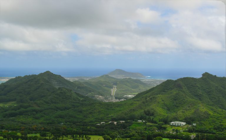 Colinas cobertas de vegetação no Havaí, com o mar ao fundo.