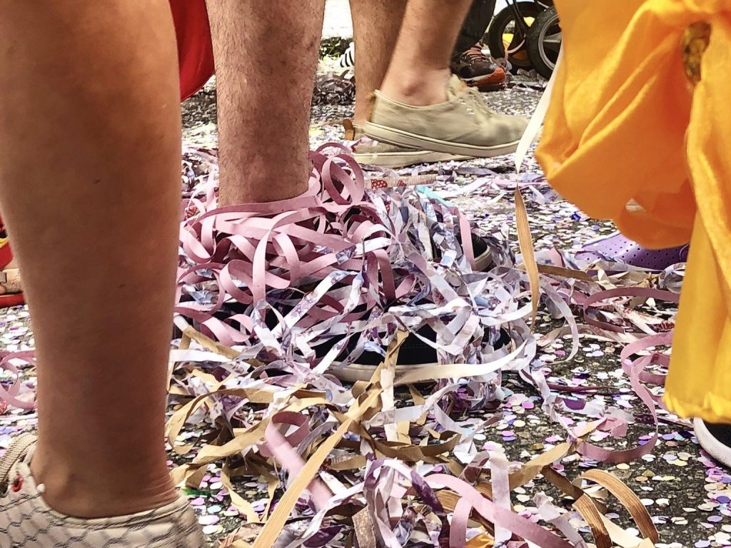 Serpentina enrolada nos pés de pessoas no carnaval de rua.