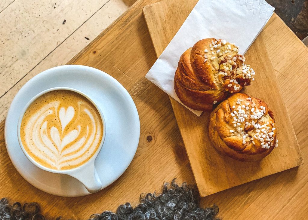 Xícara de café com leite e dois bolinhos de canela suecos.